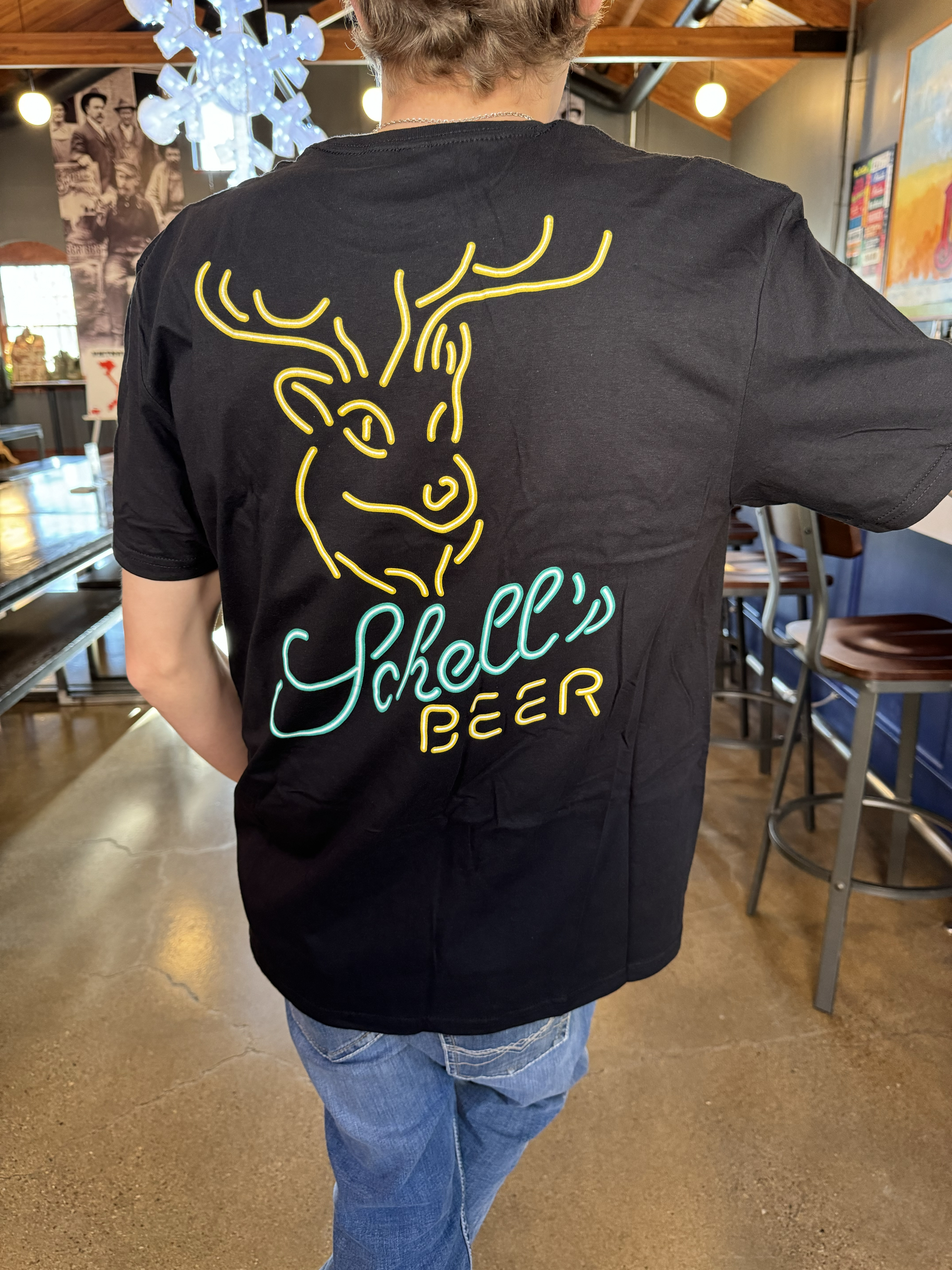 Black T-shirt with neon style Schell logo on front and back.