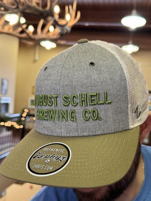 Green, grey and white baseball hat with Schell embroidered on front in green.