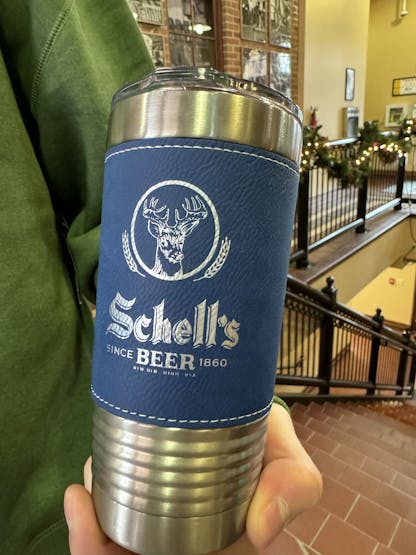 Blue leather wrapped tumbler with Schell logo on front.