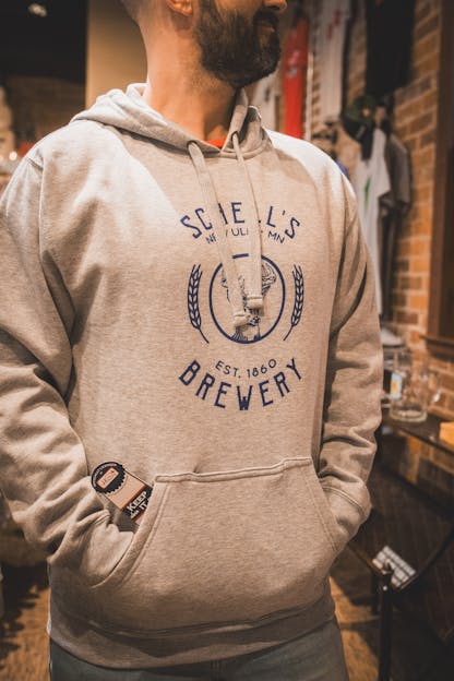 Grey hooded sweatshirt with Schell logo on front and bottle coozie inside front pocket.