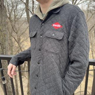 Charcoal grey quilted button up jacket with Grain Belt logo on left lapel.