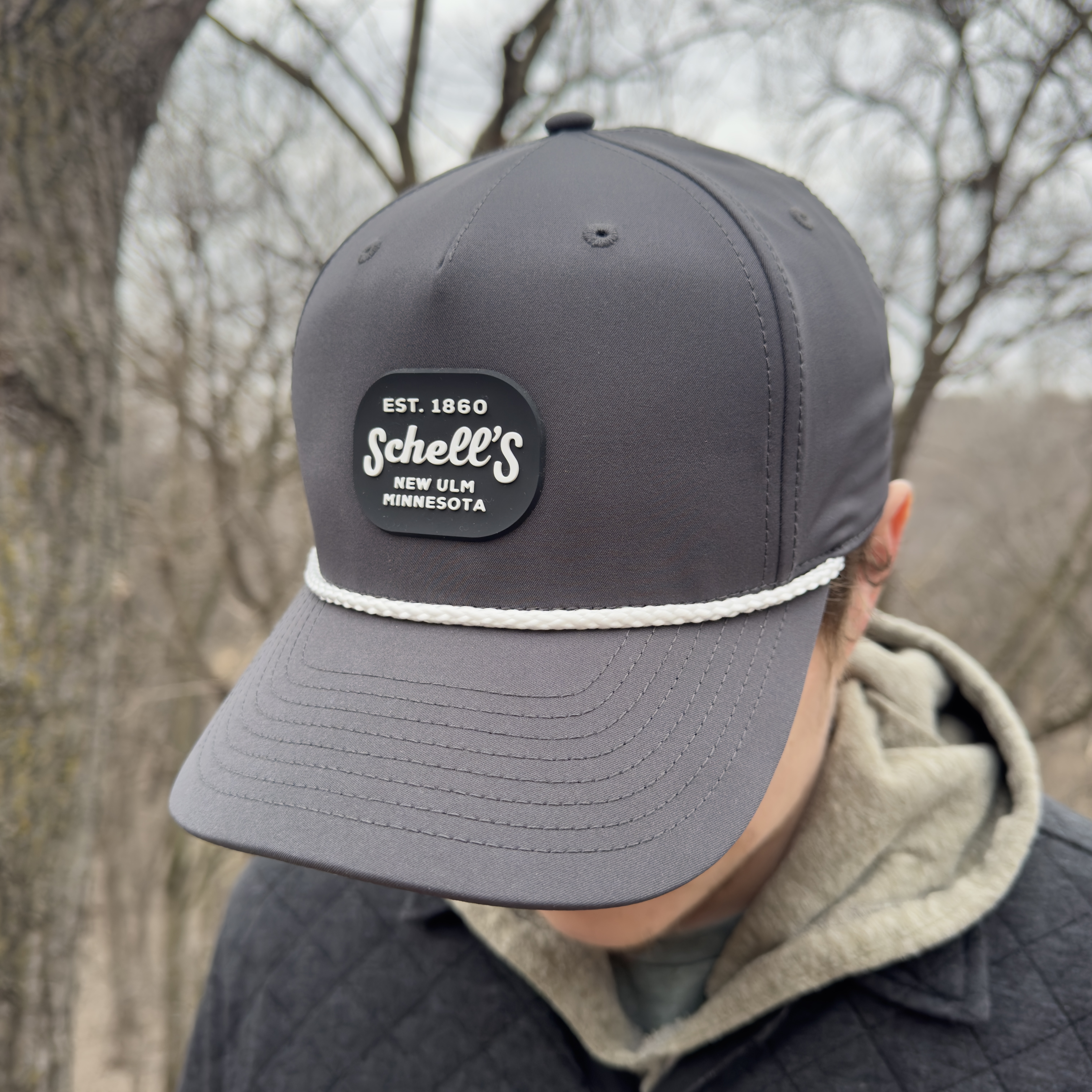 Grey hat with white rope on bill and Schell patch on front.