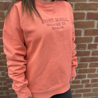 Coral colored crew neck sweatshirt with Schell logo on front.