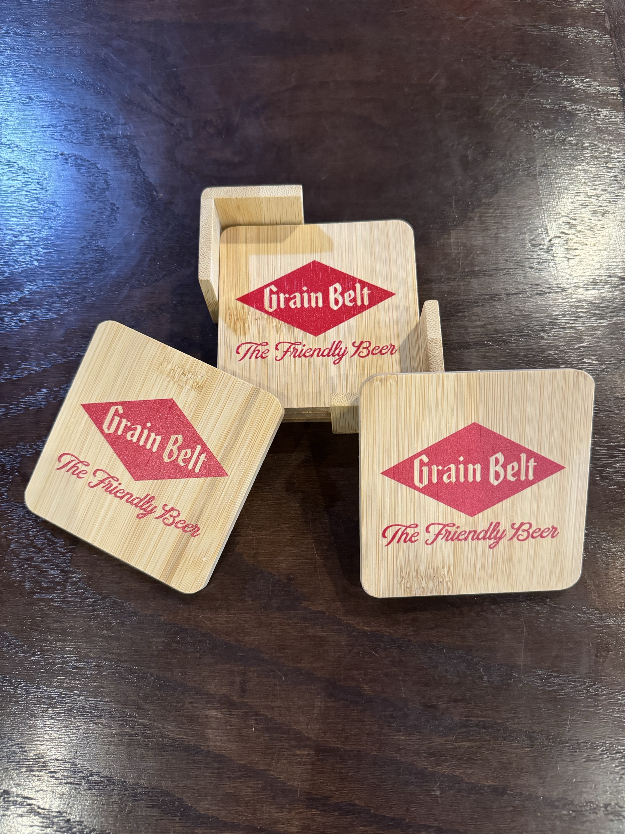Four wooden coasters with holder and Grain Belt logo printed on the top.