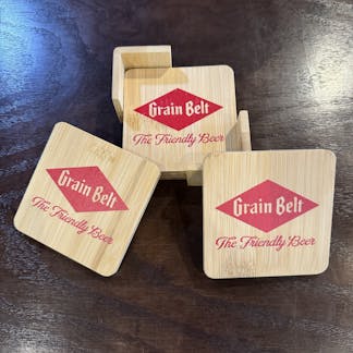 Four wooden coasters with holder and Grain Belt logo printed on the top.