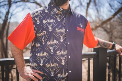 Red and black Hawaiian style shirt with Schell logo on left lapel.