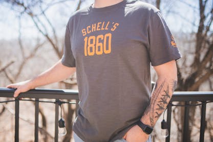 Grey t-shirt with Schell logo on front and left sleeve.