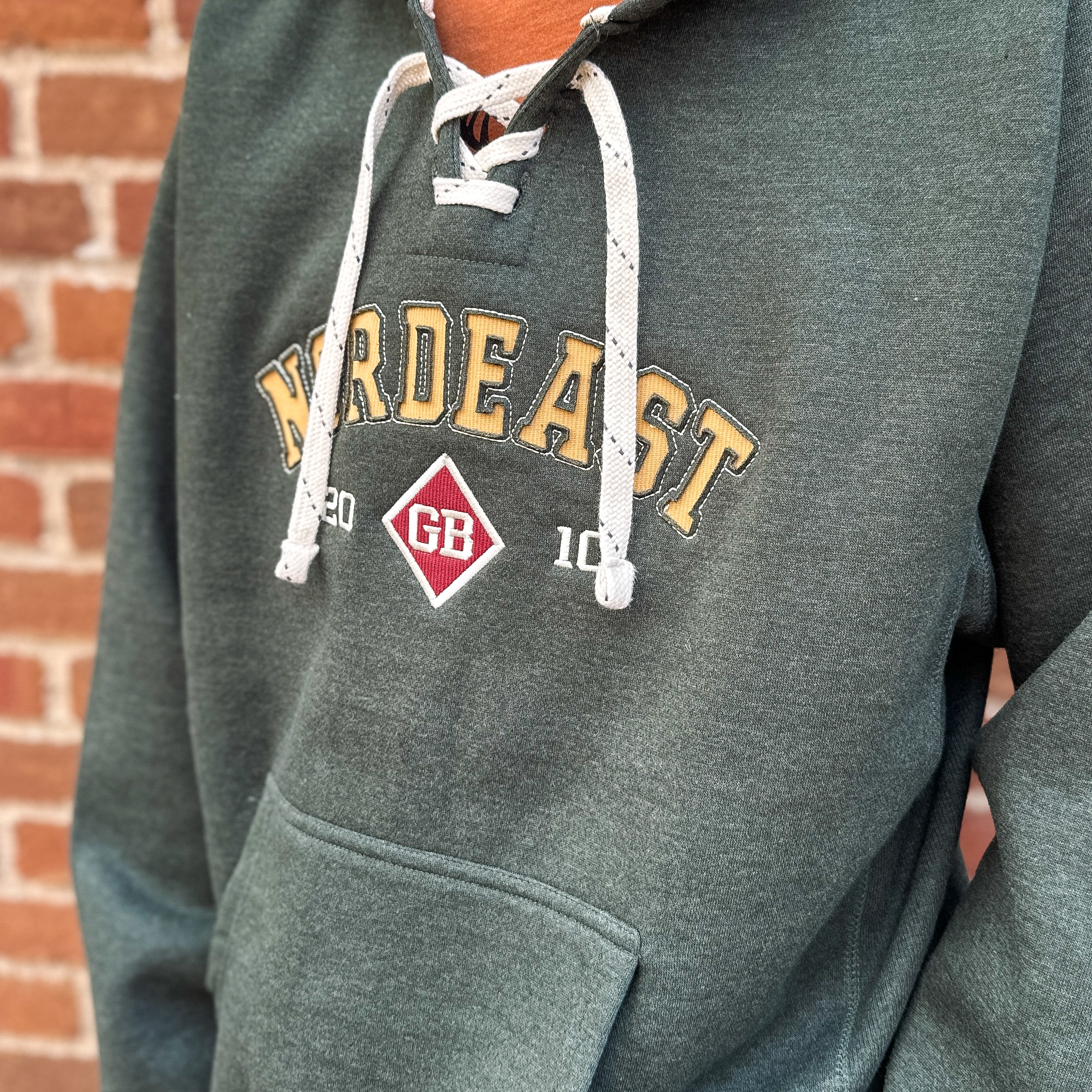 Green hooded sweatshirt with hockey lace strings and Nordeast logo on front.