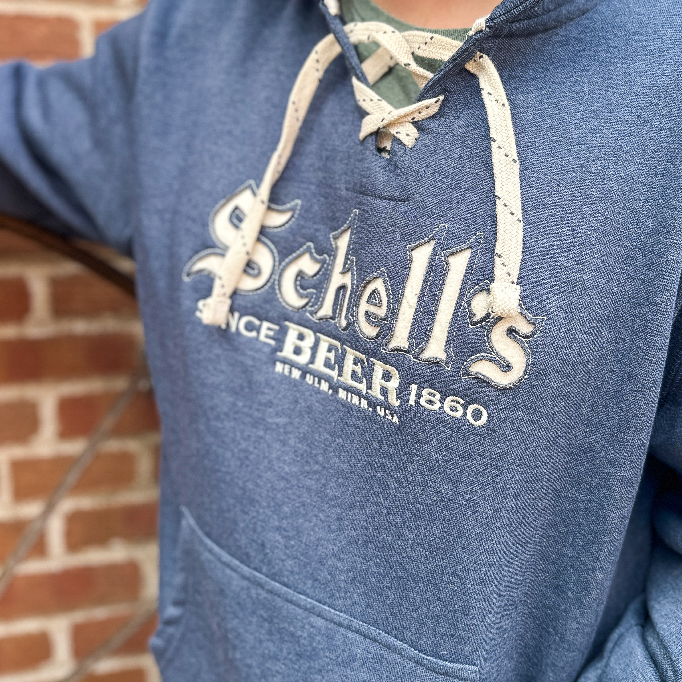 Navy hooded sweatshirt with hockey lace strings and Schells logo on front.