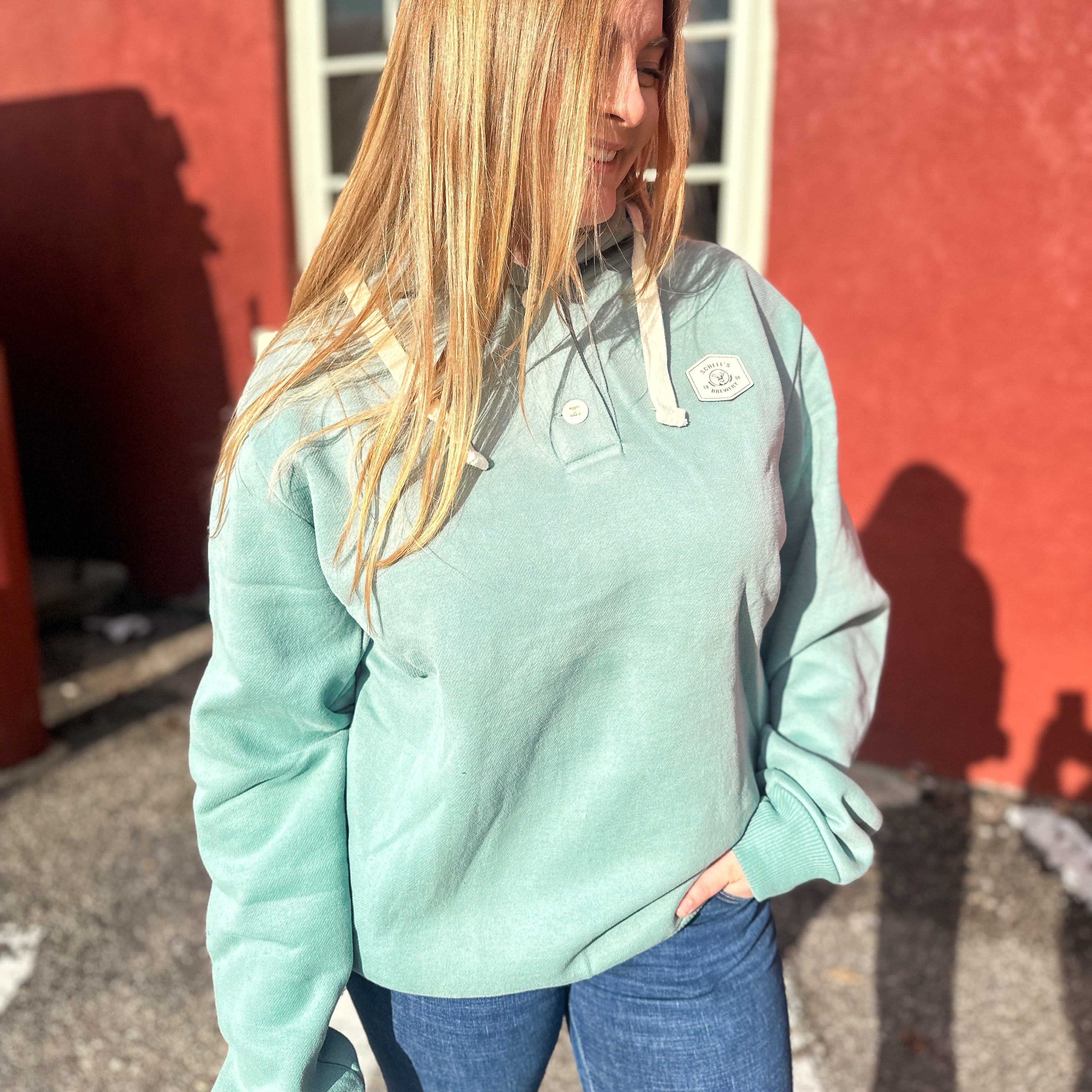 Greenish blue hooded sweatshirt with marble Schell patch on front.