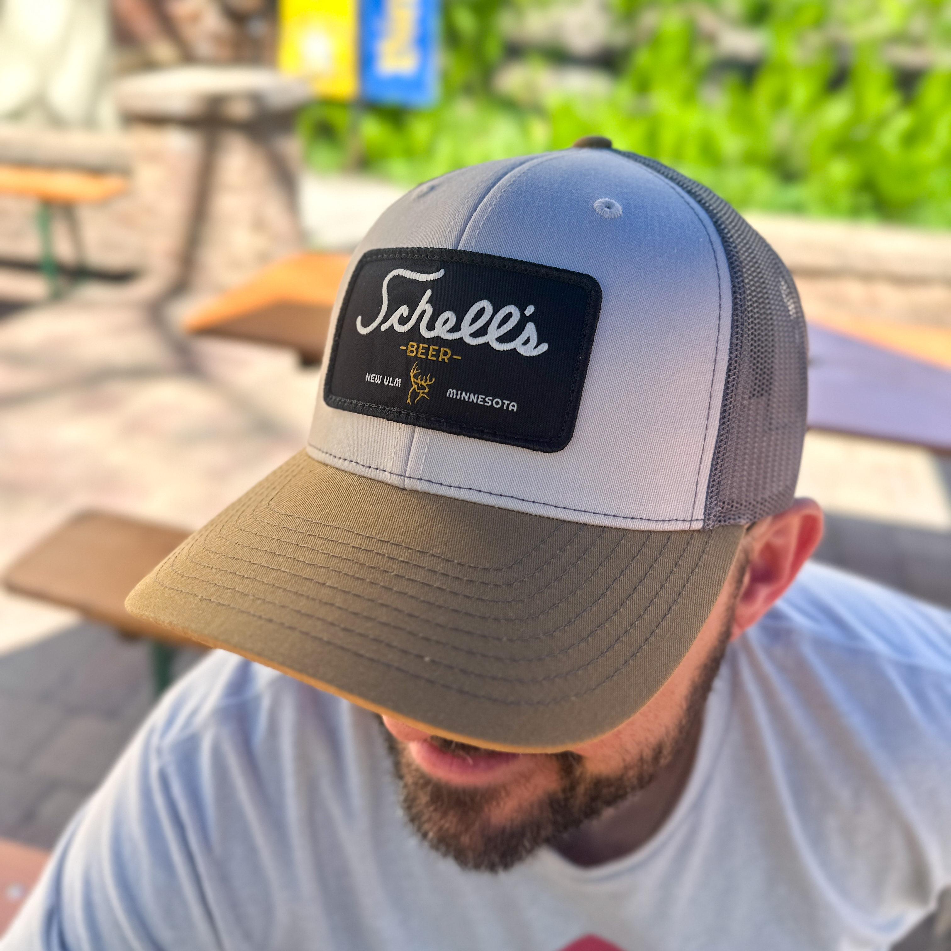 Khaki, white, and grey baseball hat with Schell Patch on the front.