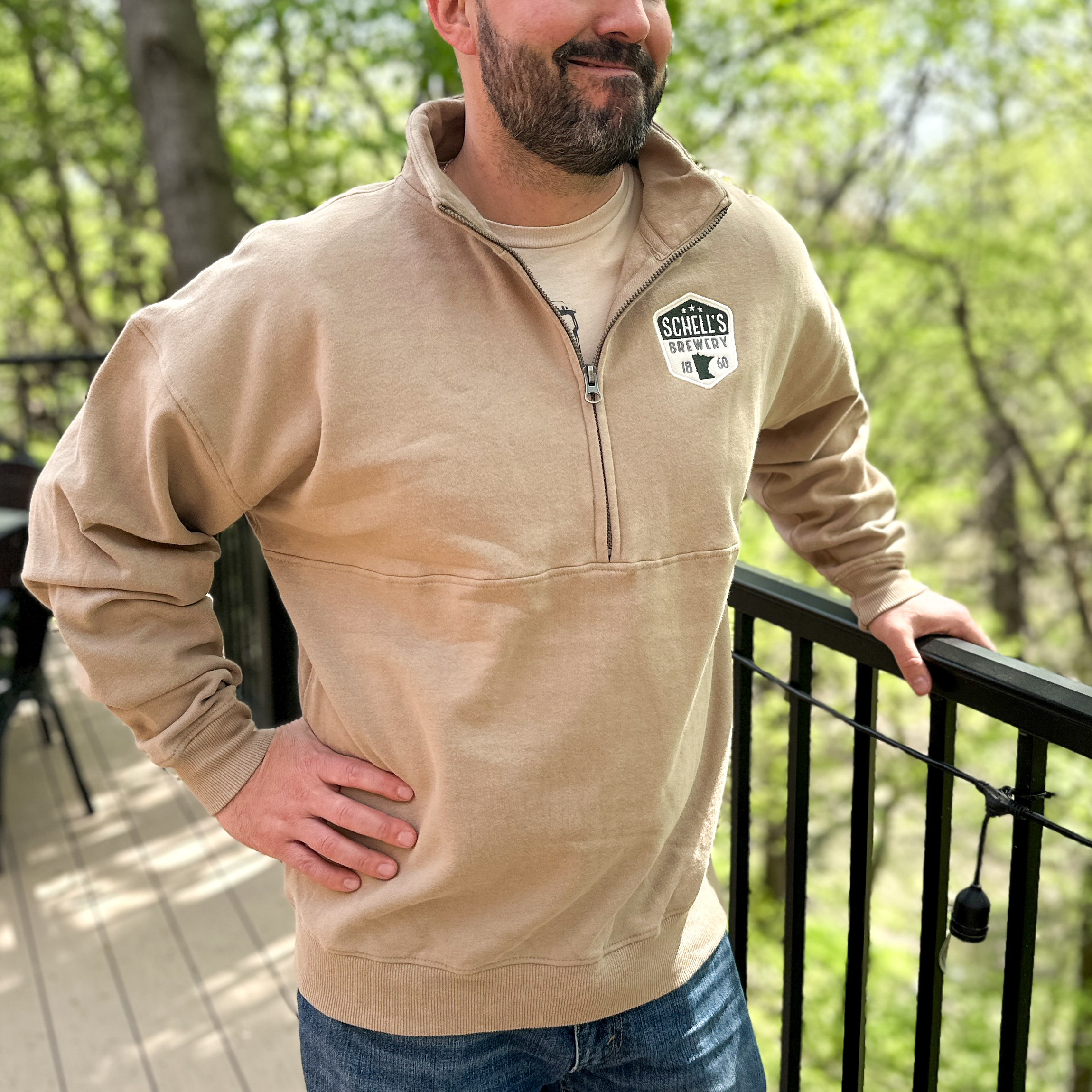 Khaki brown half zip sweatshirt with Schell patch on left lapel.