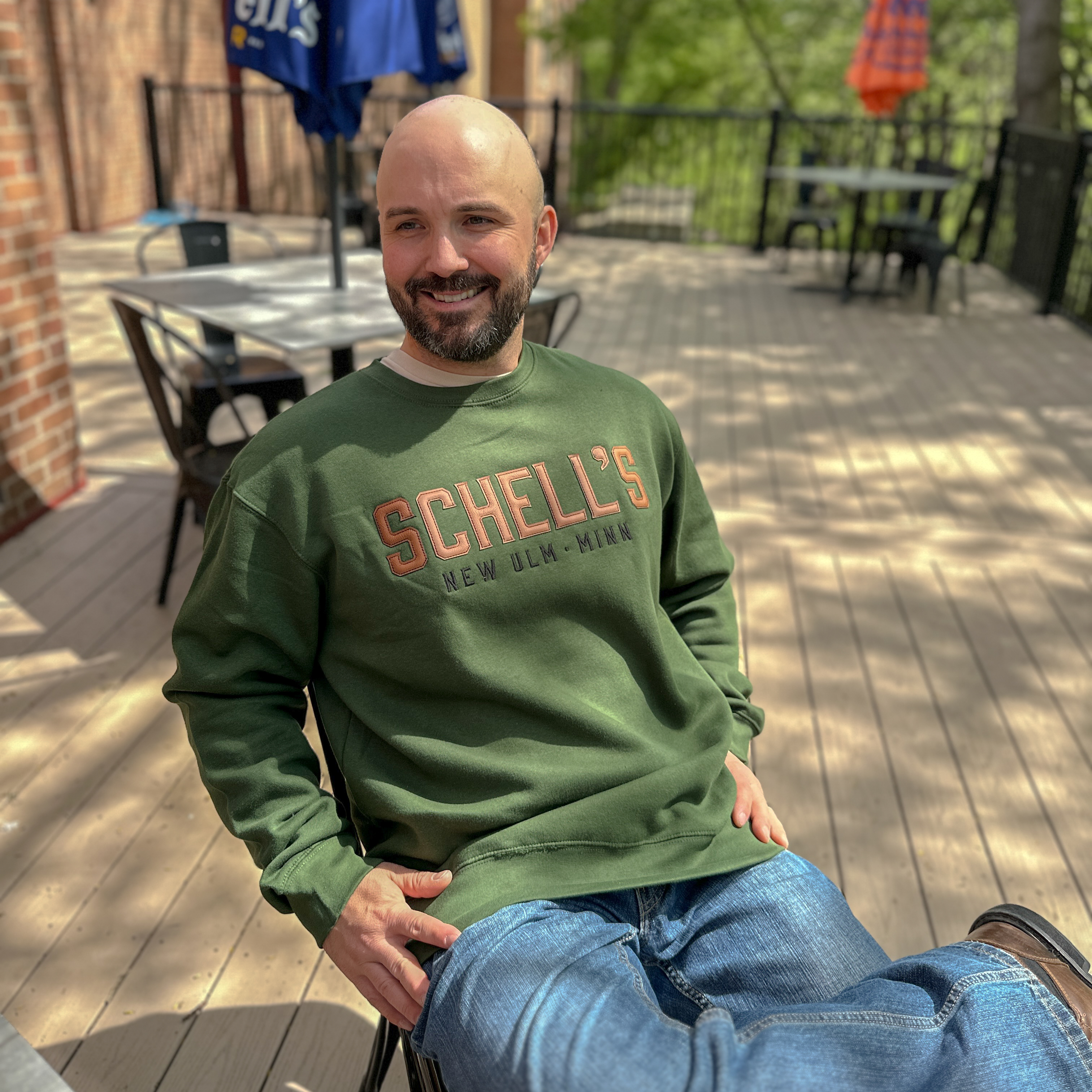 Forest green crew sweatshirt with leather letters across the chest spelling Schells.