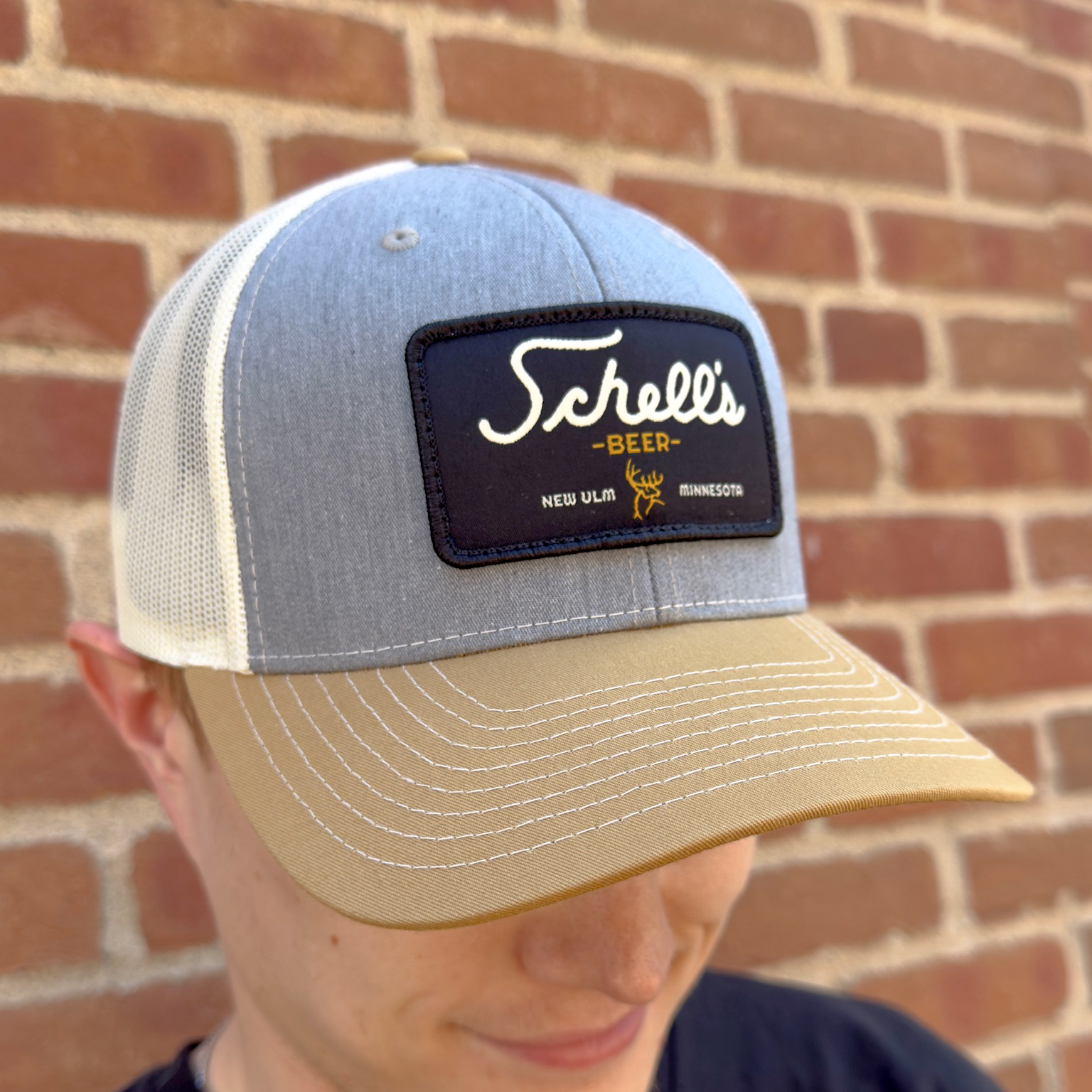 Tan, grey and white baseball hat with Schell patch on the front.