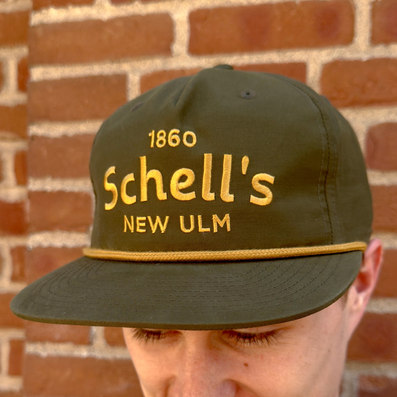 Green baseball hat with gold rope and Schells on the front.