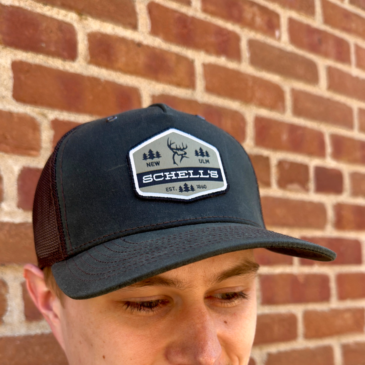 Olive and dark brown baseball hat with Schell patch on the front.
