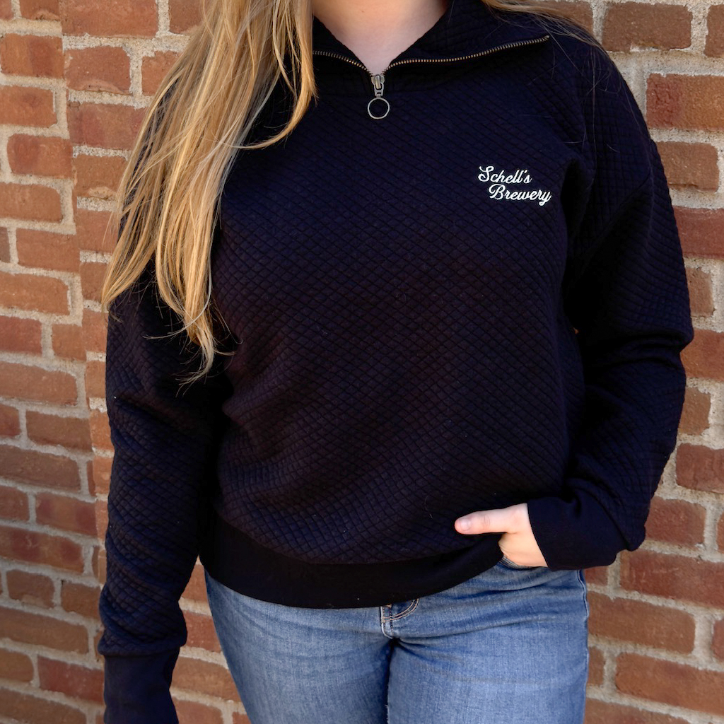 Black quarter zip sweatshirt with Schells on the left lapel.