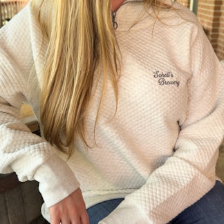 Oatmeal colored quarter zip sweatshirt with Schell logo on the front left lapel.
