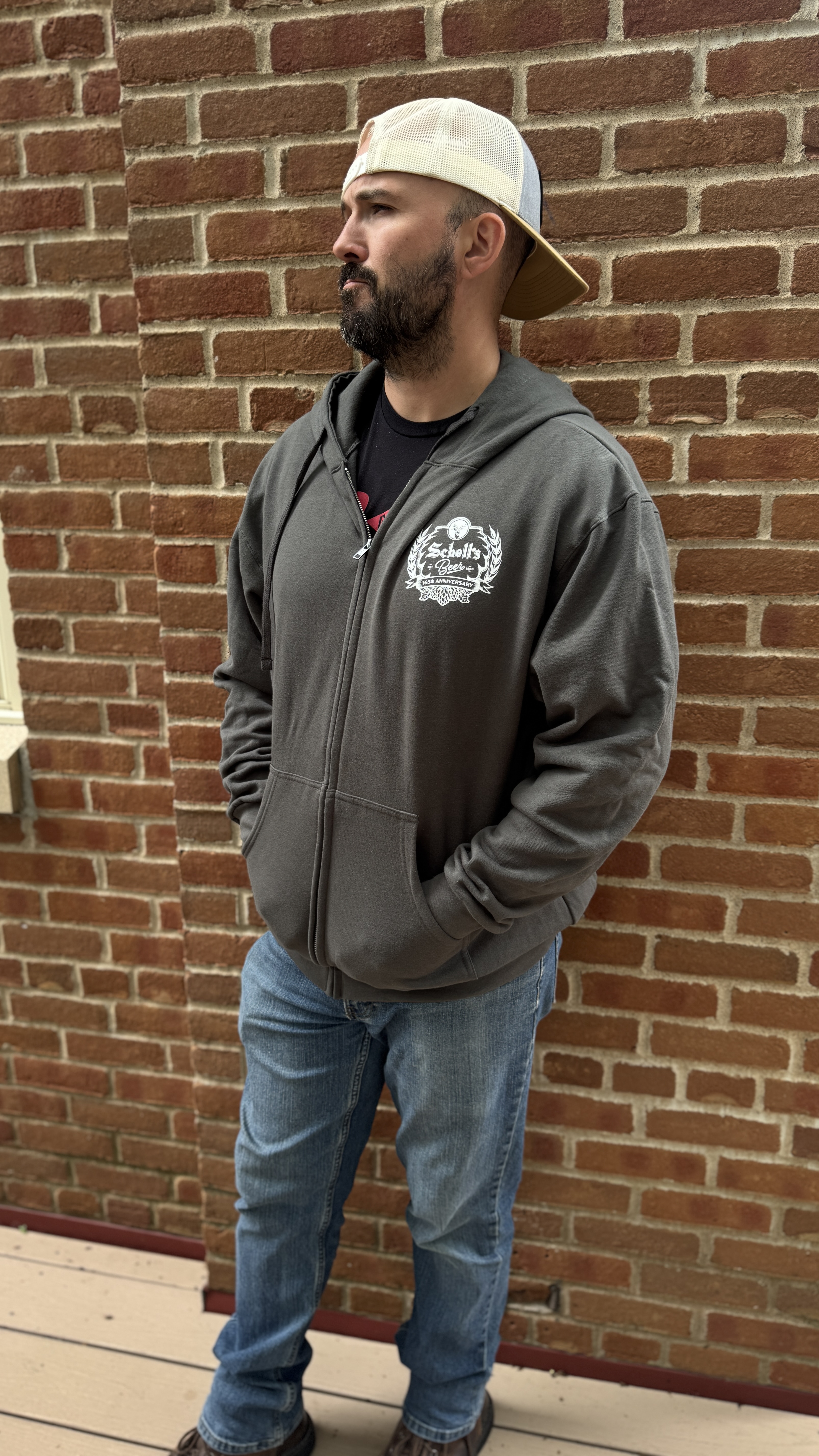 Grey colored full zip sweatshirt with a hood and the Schell 165th anniversary logo on the front left lapel.