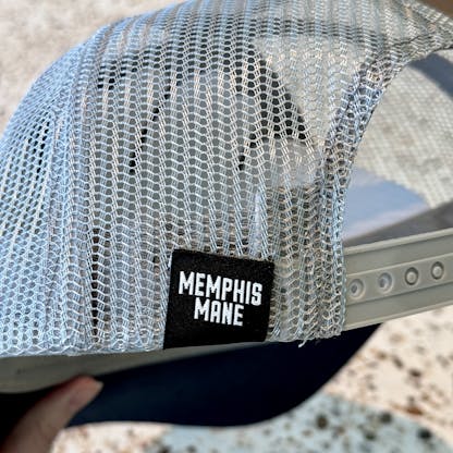 close up of navy and grey trucker with a tag that reads memphis mane