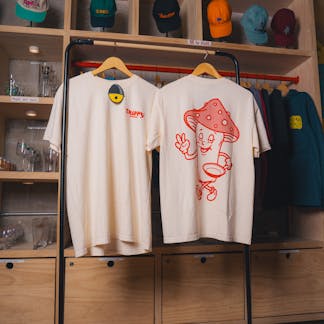 Image of trippy kitchen tshirts, showing a mushroom holding a pan in the back in red.