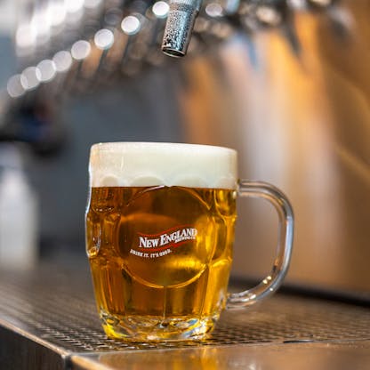 New England Brewing Company branded dimple mug full of beer under tap
