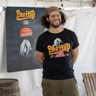 Male model smiling wearing full color Sea Hag beer logo on black t-shirt
