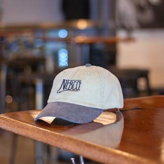 Tan NEBCO state logo hat with black brim and embroidery logo