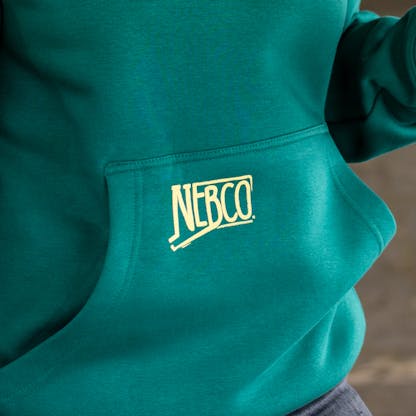 Close-up photo of yellow NEBCO state logo on front hoodie pocket of sweatshirt