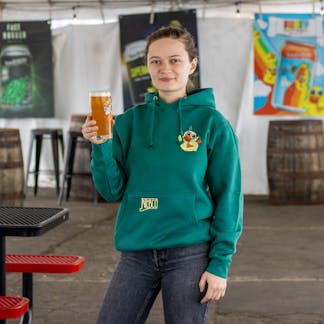 Female model wearing green fuzzy baby ducks hoodie holding a beer