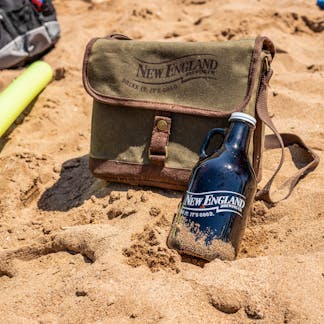 New England Brewing growler cooler and glass growler in sand