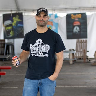 Male model wearing one color Sea Hag beer logo on black t-shirt holding a beer can