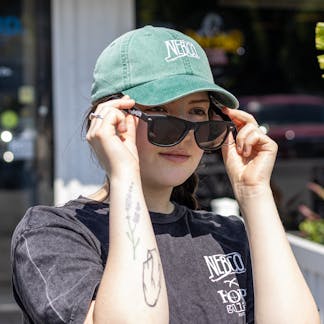 Female model taking off black New England Brewing Company sunglasses