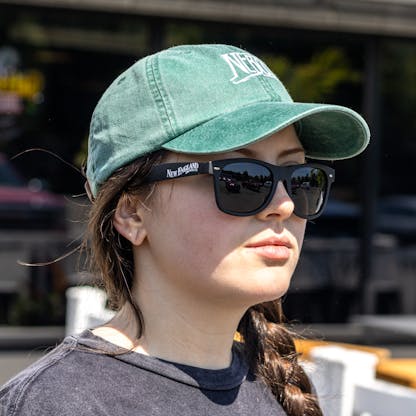 close up of female model wearing New England Brewing Company logo black matte sunglasses band