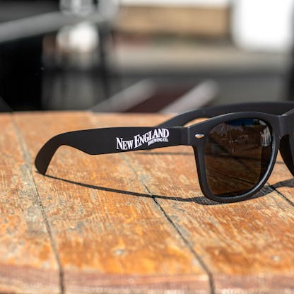 close up of New England Brewing Company logo on black matte sunglasses band