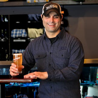 Male model smiling wearing navy blue flannel holding a beer
