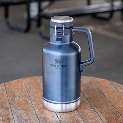 Blue 64oz Stanley insulated growler with tonal Stanley logo on table