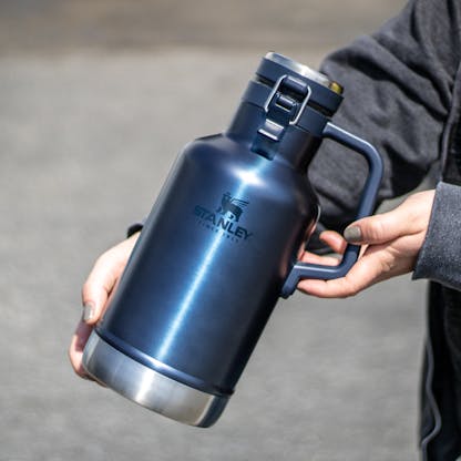 Blue 64oz Stanley insulated growler with tonal Stanley logo being held