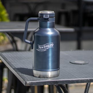 Blue 64oz Stanley insulated growler with white England Brewing Company swoosh logo on table