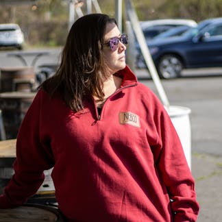 Female model wearing red quarter zip sweatshirt with NEBCO State leather applique