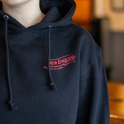 close-up of red New England Brewing Company swoosh on hooded pullover sweatshirt