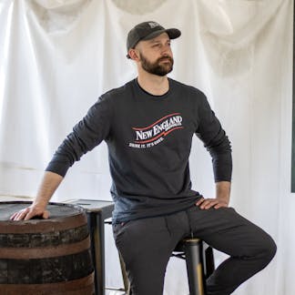 Male Model wearing long sleeve gray t-shirt with New England Brewing Company swoosh logo