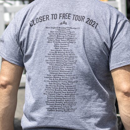 Close up of Closer to Free Tour sponsor list on back of gray T-shirt