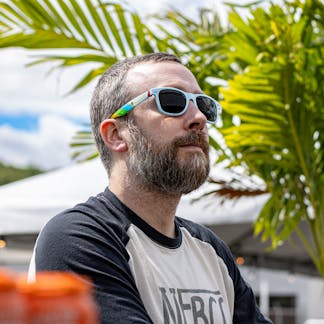 Male model wearing sunglasses with plant in background