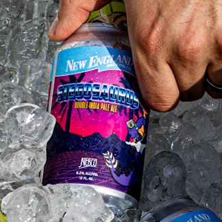Hand reaching down into cooler and lifting beer can out. Ice surrounding can