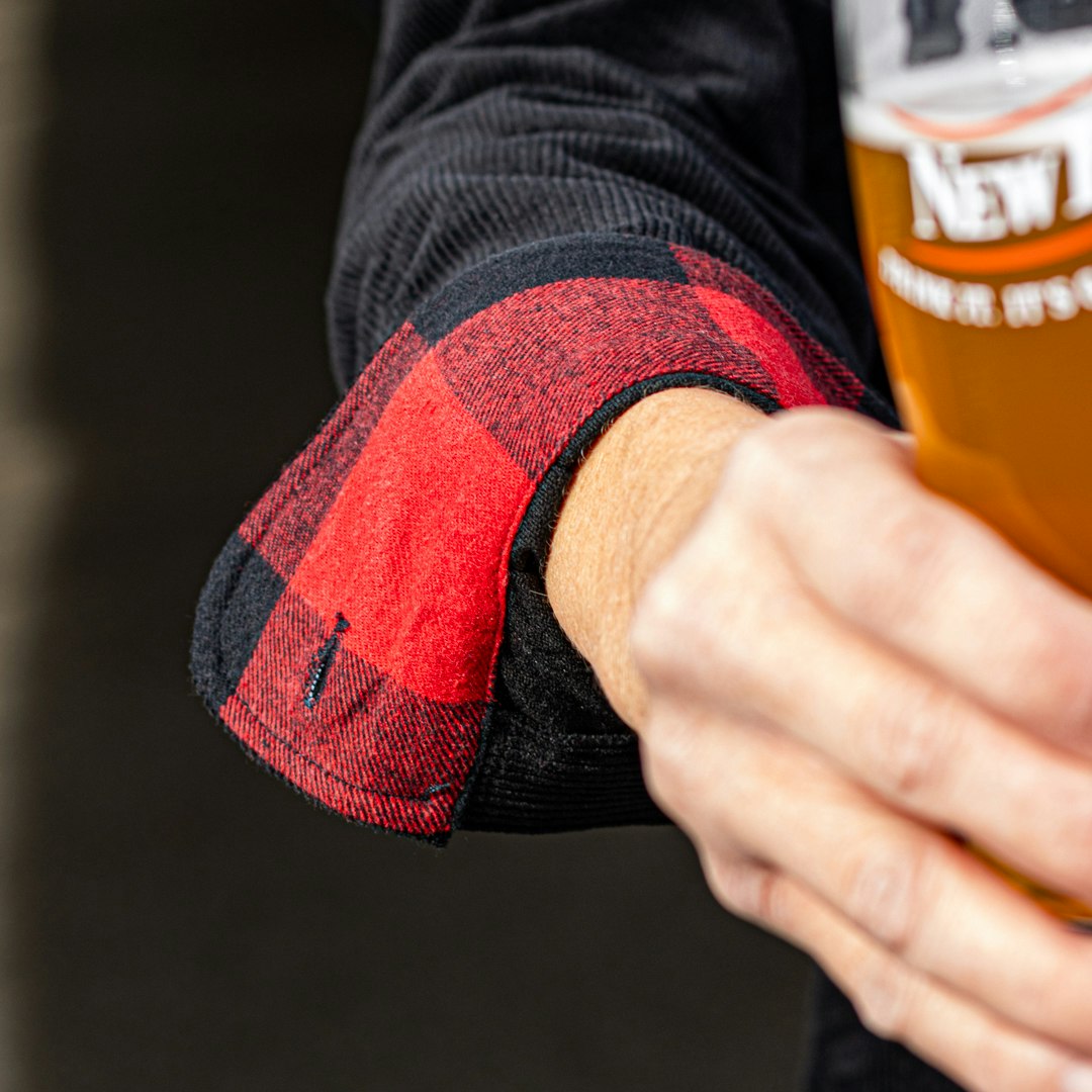 Close up of jacket sleeve. Sleeve rolled back revealing red flannel pattern