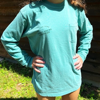 person modeling long sleeve t-shirt, seafoam color with pocket on left chest and branding on right chest