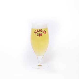 a chalice filled with beer. the front of the glass features a leaf logo and the text Allagash.