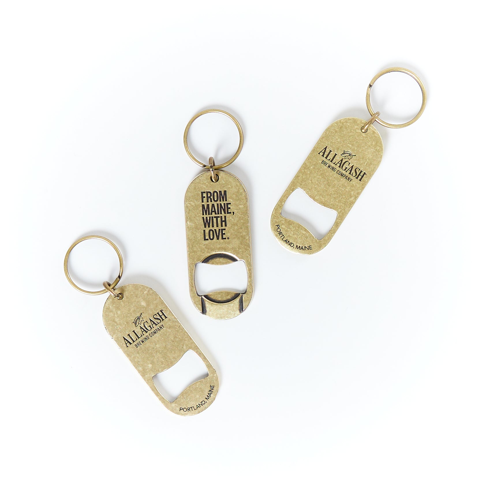 a metal brass colored bottle opener with keyring. One side reads Allagash, the other From Maine, With Love