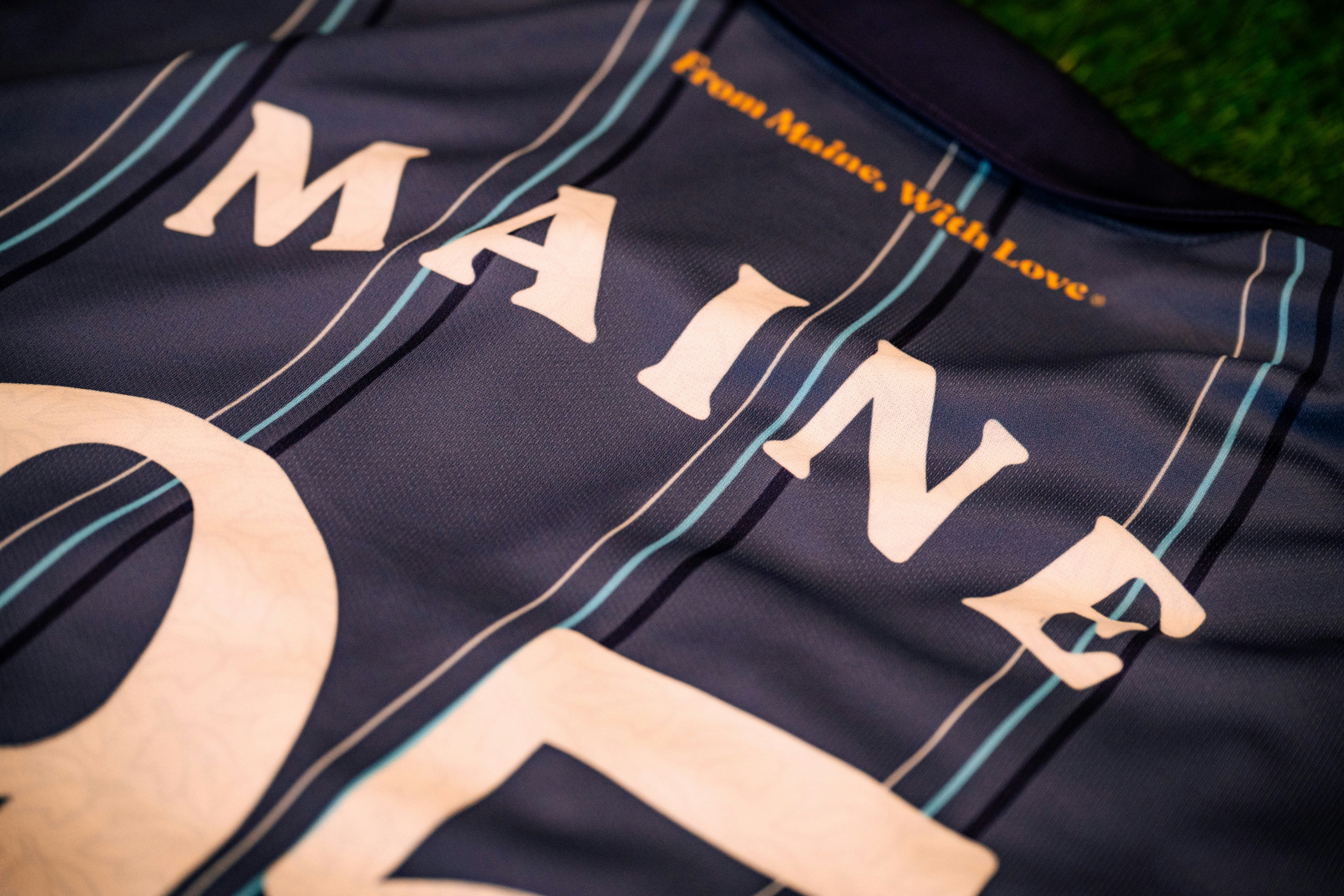 a close up of the word Maine on the back of a blue striped jersey